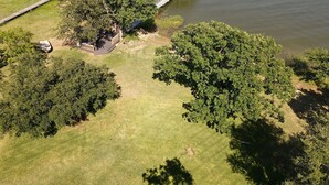 An aerial view of a lakeside property with a dock, a covered boat house, and a well-maintained lawn. - Quiet lakefront home. on Lake Leon, Eastland TX.  90 min to Fort Worth. (Eastland)
