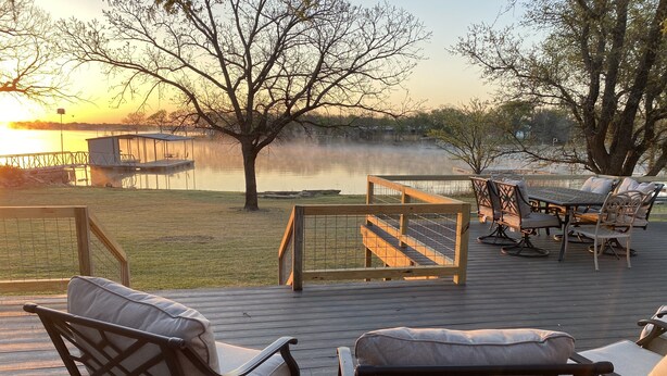 A deck with outdoor furniture, a wooden table, and a view of a lake at sunset. - Quiet lakefront home. on Lake Leon, Eastland TX.  90 min to Fort Worth. (Eastland)