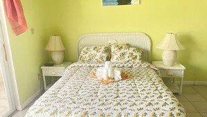 Ein Schlafzimmer mit einem Bett, zwei Nachttischen, einem Gemälde und einem Fenster.