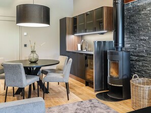 A modern kitchen with a built-in stove, a dining area with a round table and chairs, and a hanging light fixture.