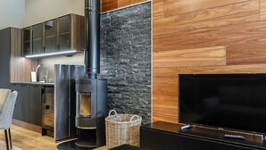 Eine moderne Küche mit eingebautem Holzofen, einem Flachbildfernseher und einer Essecke mit schwarzem Tisch und Stühlen.