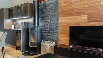 Un espacio habitable moderno con estufa de leña, televisor de pantalla plana y zona de cocina.
