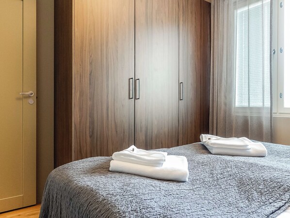 Une chambre à coucher avec un lit, une armoire et une fenêtre équipée de stores.