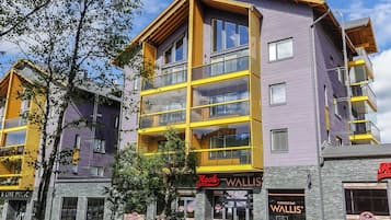 Un immeuble à plusieurs étages, doté d’une façade jaune et violette, qui abrite un restaurant appelé « Hook Restaurant » et un bar karaoké appelé « Wallis’ Karaoke Bar ».