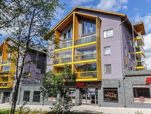 A multi-story building with a yellow and purple facade, featuring a restaurant named 'Hook Restaurant' and a karaoke bar named 'Wallis' Karaoke Bar'.