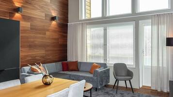 Una sala de estar moderna con una pared de acento de madera, un sofá gris, una mesa de comedor de madera y un sillón gris.