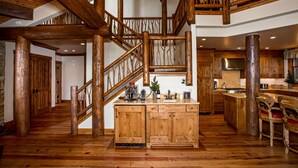 A wooden staircase with a rustic design, a kitchen area with wooden cabinets, and a dining area with wooden chairs.