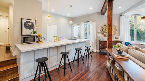 A modern kitchen with a white island, black bar stools, and a wooden floor. - Amazing Apartment attached to historic home in Pasadena! (Pasadena)