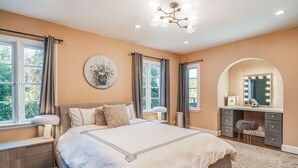 A bedroom with a large bed, a vanity with a mirror, and a desk. - Amazing Apartment attached to historic home in Pasadena! (Pasadena)