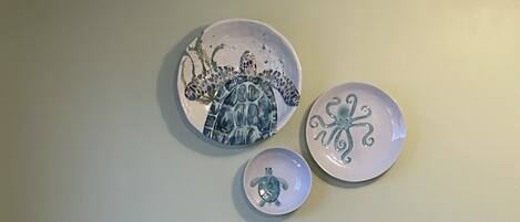 Trois assiettes en céramique ornées de motifs de tortues de mer, accrochées à un mur uni.
