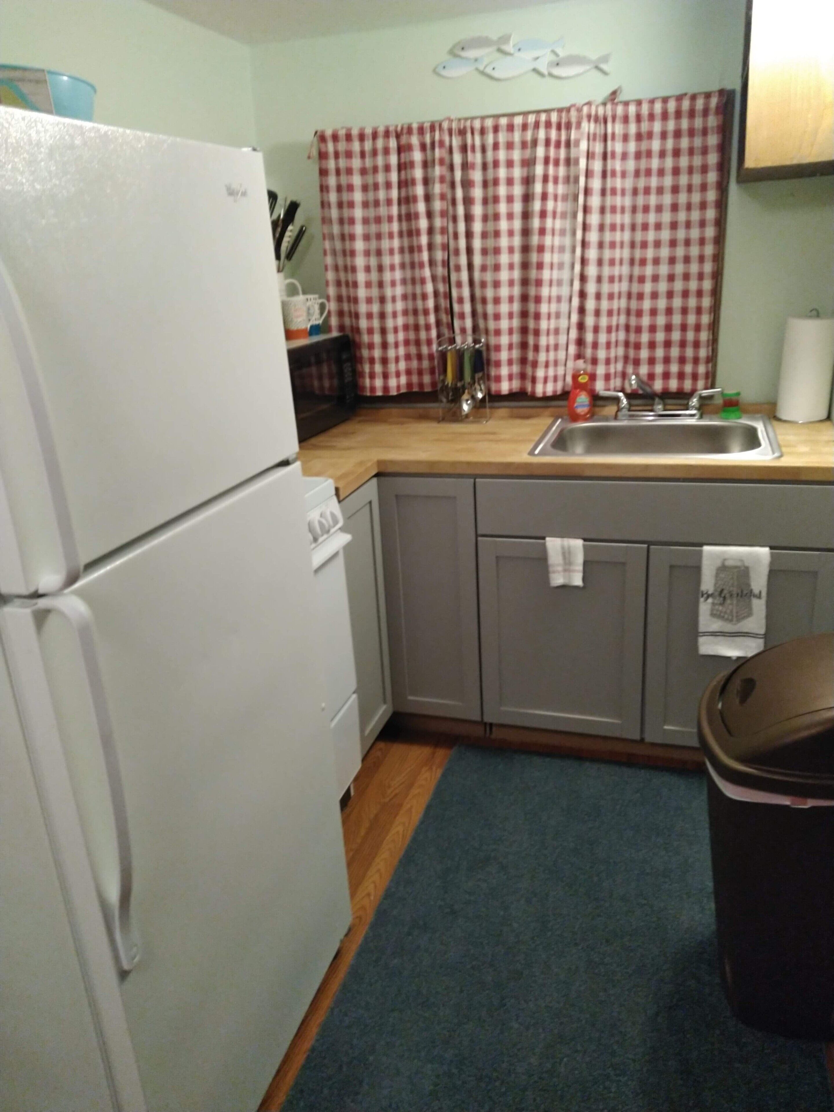 A kitchen with a white refrigerator, a sink, and a wooden countertop.