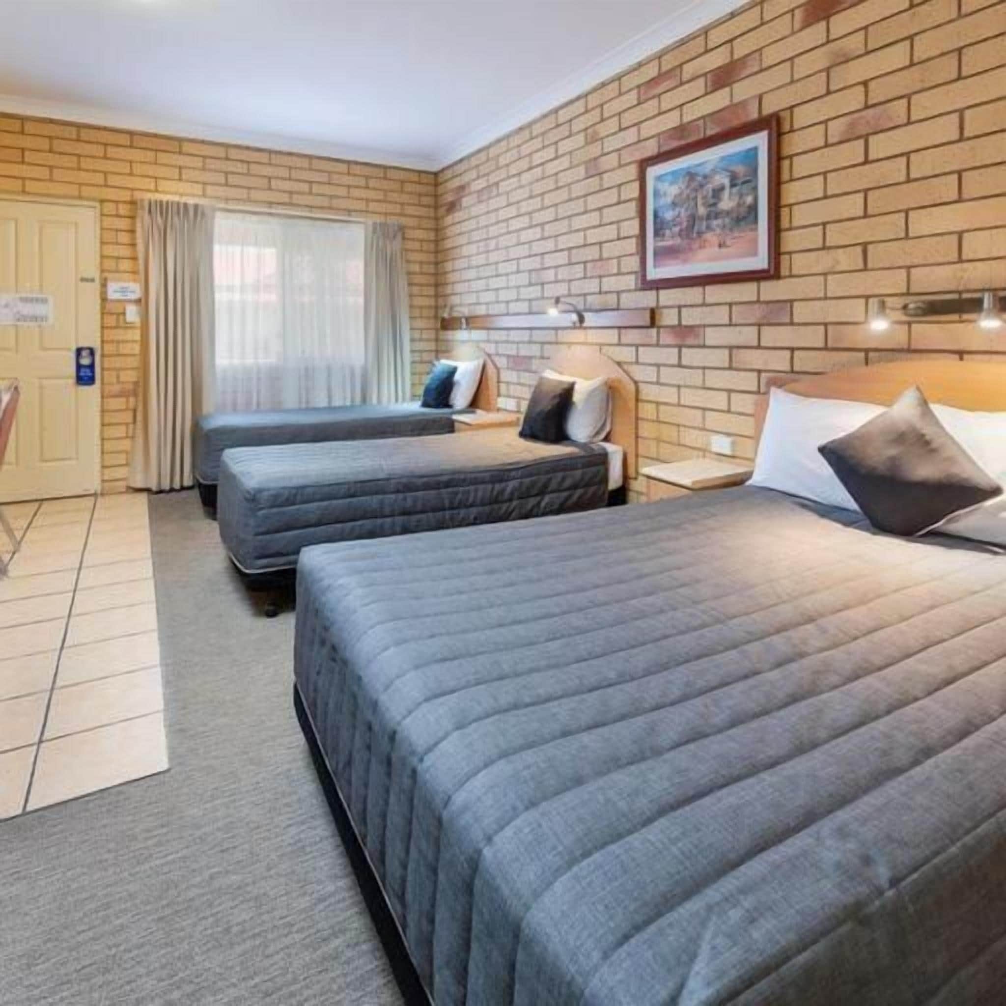 A hotel room with two beds, a desk, and a window with curtains.