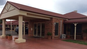 A building with a covered entrance, brick walls, and a red roof. - Roma Mid Town Motor Inn (Roma)