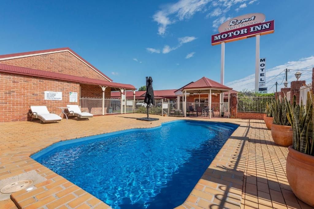 A brick building with a pool, lounge chairs, and a sign for the Motor Inn.