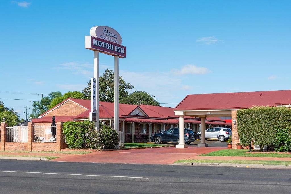 A motel with a red roof, a signboard, and a covered parking area.