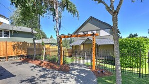 Ein Wohnhaus mit befestigter Auffahrt, einer hölzernen Pergola und einem gepflegten Rasen.