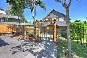 A residential property with a gated driveway, a wooden pergola, and a well-maintained lawn.