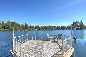A wooden dock with metal railings, two chairs, and a table.