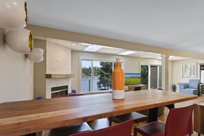 A spacious dining area with a long wooden table, red chairs, and a large orange and white vase. - Star Lake Waterfront Estate (Auburn)