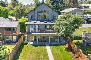 A modern two-story house with a covered patio, a fenced backyard, and a well-maintained lawn.