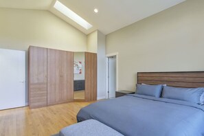 A bedroom with a large bed, wooden wardrobe, and a skylight. - Star Lake Waterfront Estate (Auburn)