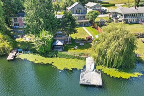 An aerial view of a residential area with a dock extending into a lake surrounded by lush greenery and houses. - Star Lake Waterfront Estate (Auburn)