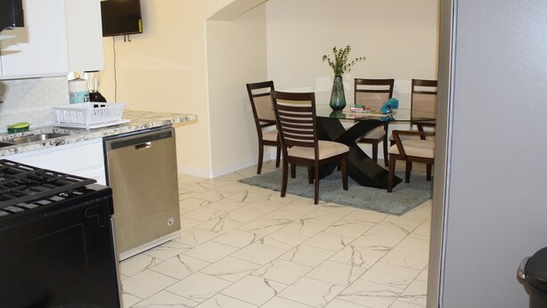 A compact kitchen with a dishwasher, stove, and a dining area with chairs and a table.
