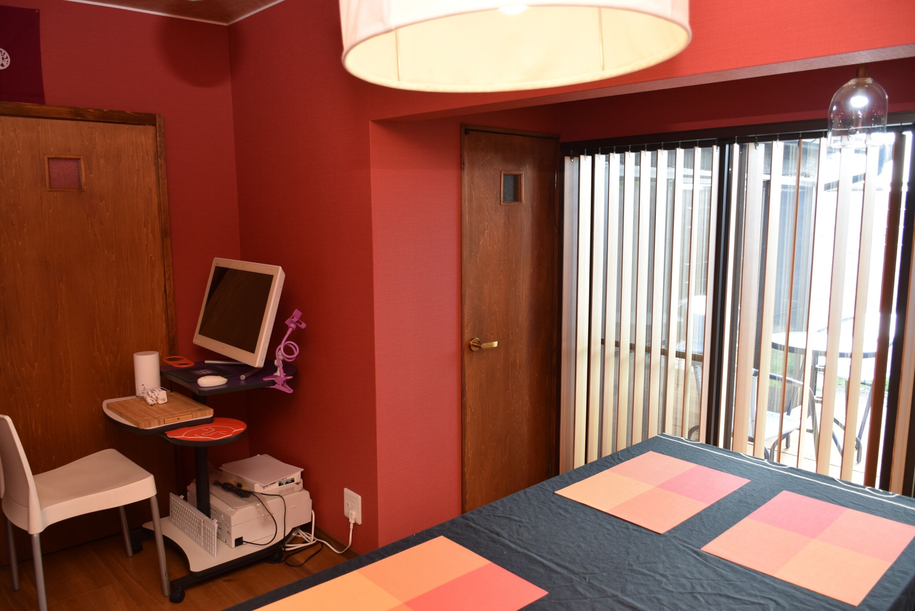 A room with a bed, a desk with a computer, a chair, and a window with blinds.