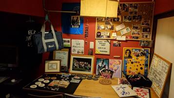 A room with a desk cluttered with memorabilia, a hanging bag, and various photos and posters on the wall.