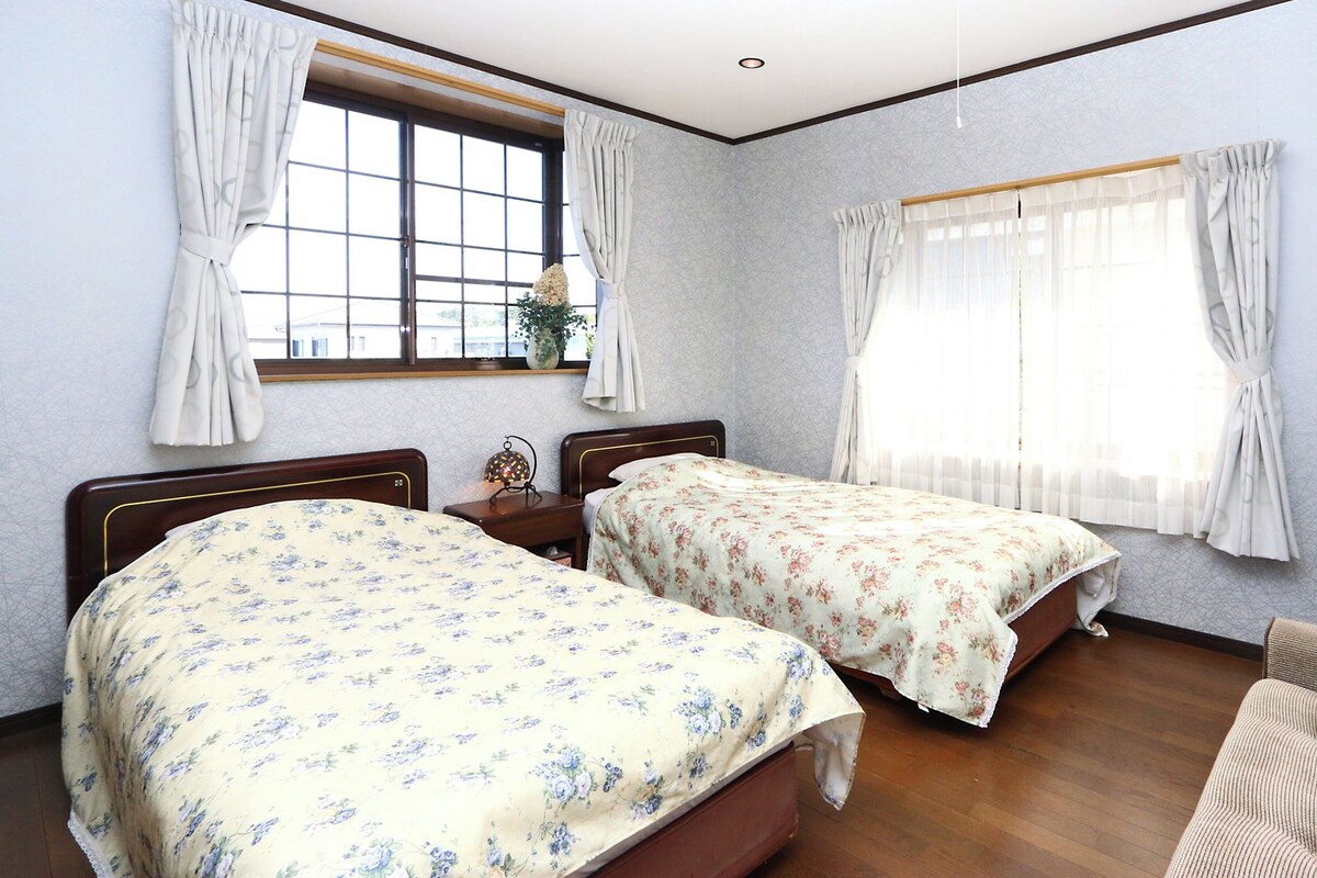 A hotel room with two beds, a TV, and a window with curtains.