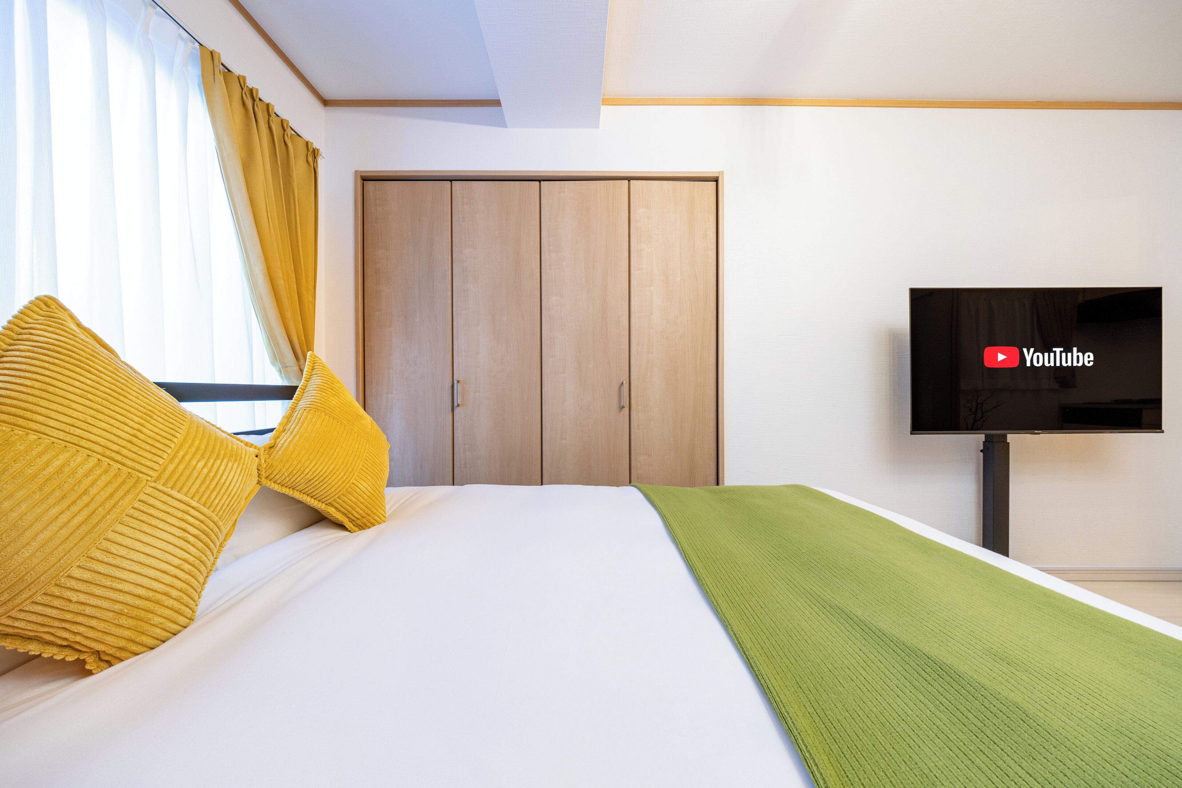 Habitación de hotel con cama, televisión, armario y ventana con cortinas.