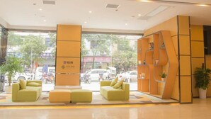 A modern hotel lobby with a reception desk, seating area, and large windows offering a view of the street. - Chonpines Hotel (Guangyuan)