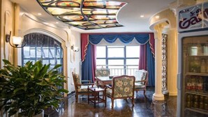 A dining area with a stained glass ceiling, a large window with blue curtains, and a bar with a sign. - Chonpines Hotel (Guangyuan)