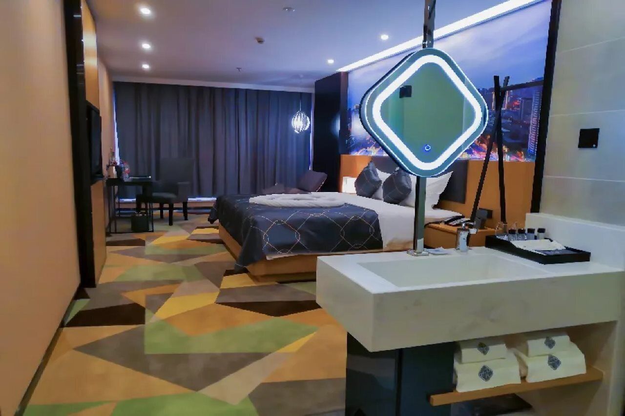 Ein modernes Hotelzimmer mit einem großen Bett, einem Schreibtisch und einem Badezimmer.