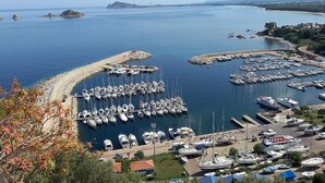 A marina with numerous boats docked, surrounded by a coastal landscape with mountains in the background. - Base Camp Ogliastra - Flat Green  (Santa Maria Navarrese)