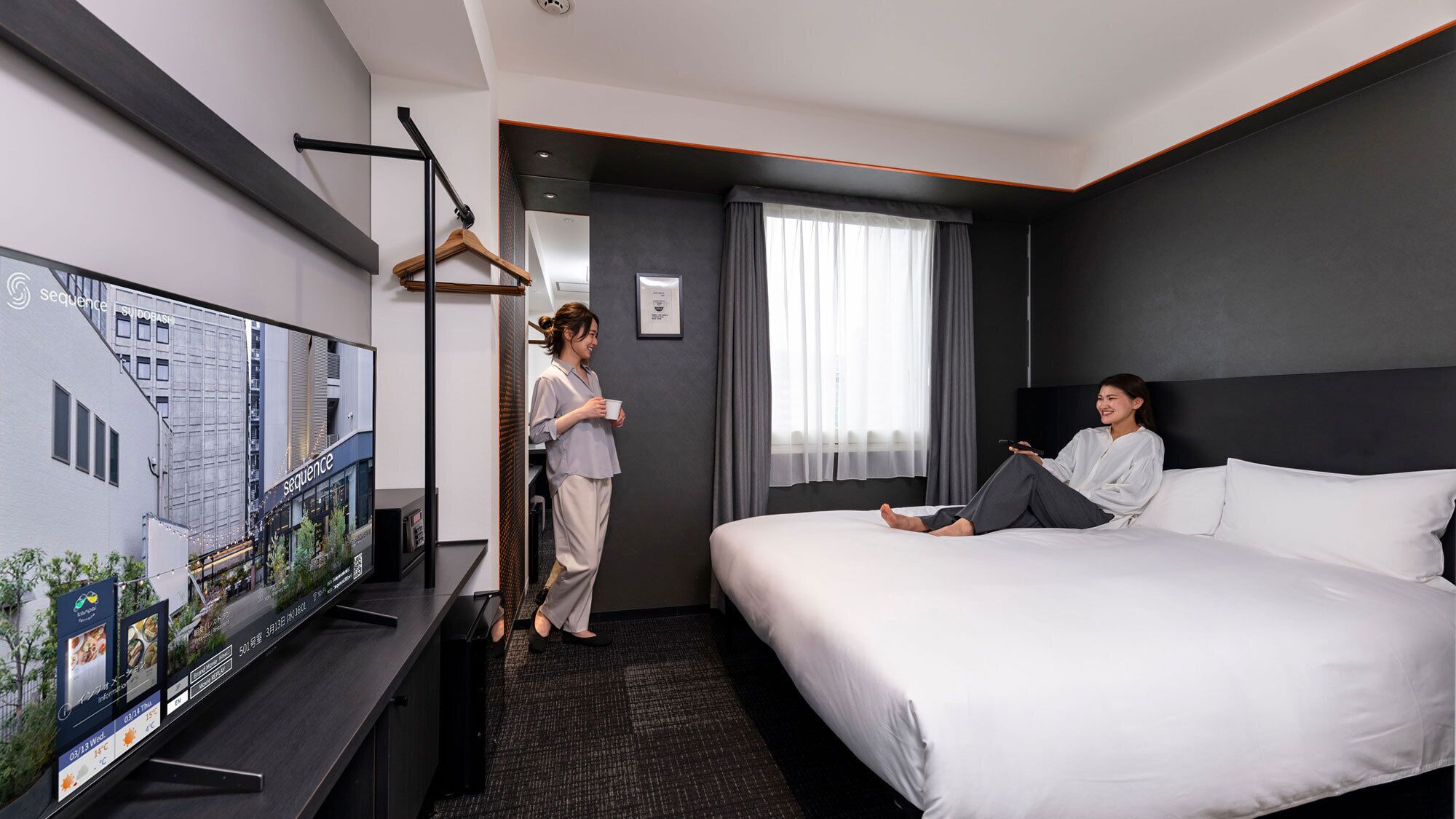 Habitación de hotel con cama, televisor, escritorio y ventana con cortinas.