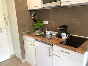 Eine moderne Küche mit integriertem Mikrowellenherd, einer Kaffeemaschine und einem Spülbecken.