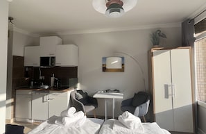 Habitación de hotel pequeña con kitchenette, comedor, cama y toallas, y vistas al exterior.