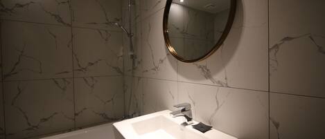 A bathroom with a white sink, a mirror, and a shower.