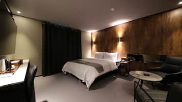 A modern hotel room with a bed, a desk, a chair, and a small table.