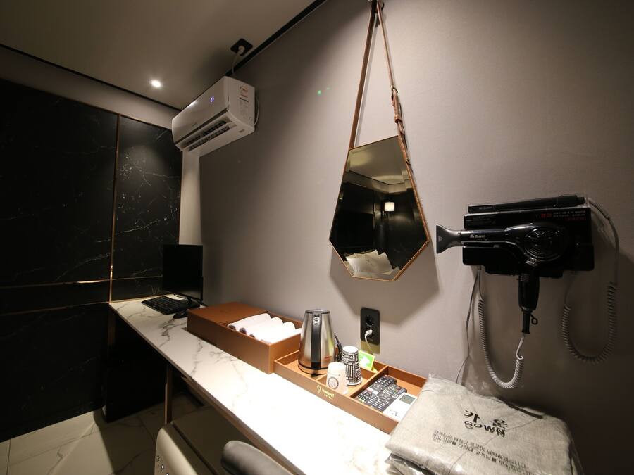 A modern bathroom with a marble countertop, a hairdryer, a mirror, and a towel rack.