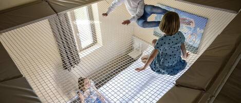 A room with a large window, a sofa, and a netted play area.