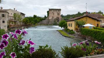 A river with a castle in the background, surrounded by buildings and greenery.