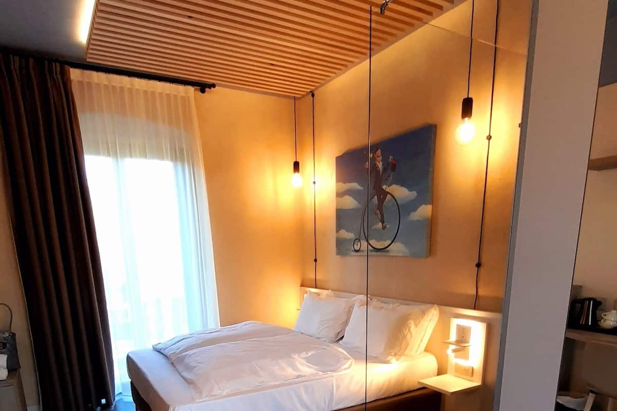 Une chambre à coucher moderne avec un lit, une table de chevet, un tableau et un luminaire au plafond.