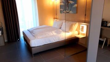Un dormitorio moderno con cama, mesita de noche, un cuadro y una lámpara en el techo.