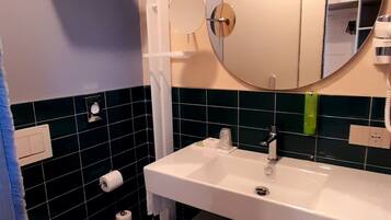 Ein modernes Badezimmer mit Toilette, Waschbecken mit Spiegel und Handtuchhalter.
