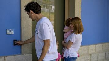 Un uomo, una donna e un bambino all'ingresso di un edificio, che interagiscono con la serratura.