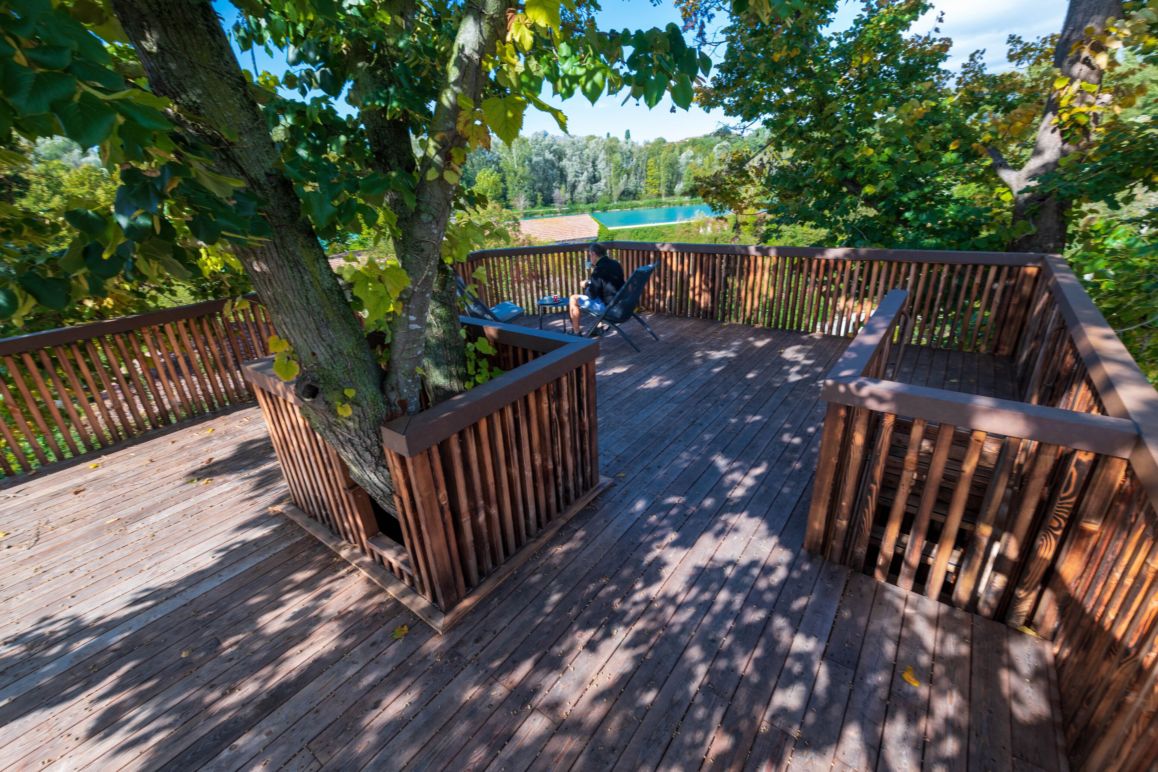 A wooden deck with a view of a lake and trees.