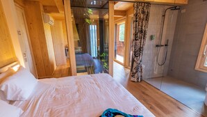 Een slaapkamer met een bed, een douche en uitzicht op een balkon.
