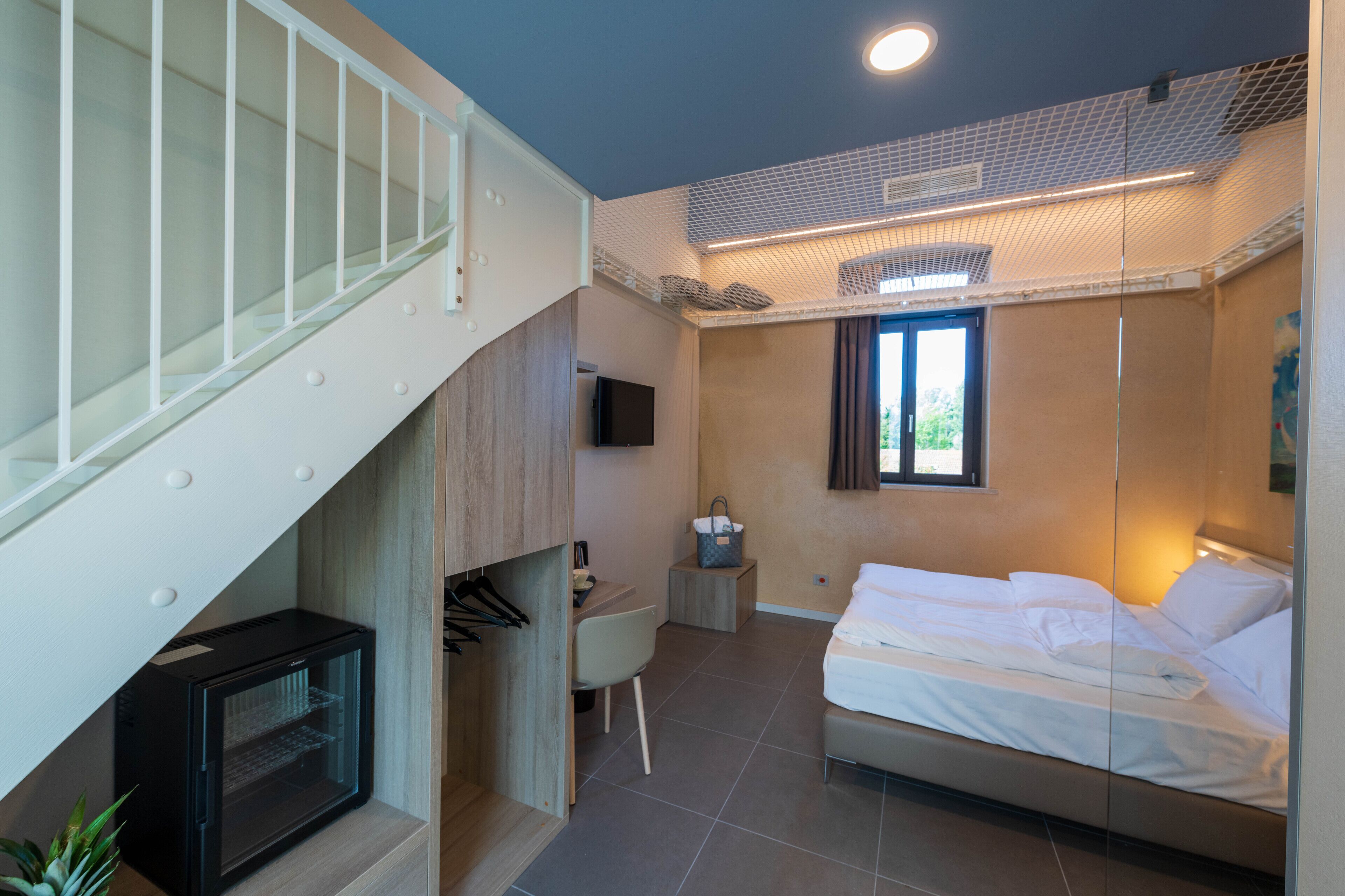Ein Schlafzimmer mit einem Bett, einem Schreibtisch, einem Fernseher und einer Treppe.